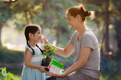 Happy Asian mother cleaning her daughter's face, Plant together