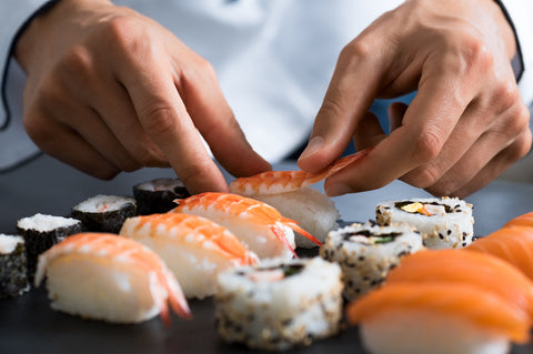 Japanese chef making sushi at restaurant.