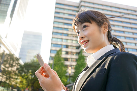 Business woman looking up with smile with her phone in hand