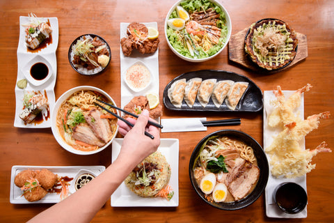 A table filled with Japanese foods including ramen, tempura, gyoza, and much more