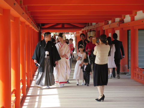 Groom, bride and family walking inside a shrine while a photographer takes them pictures in the wedding day