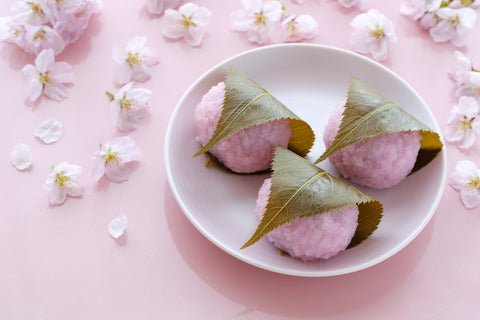 Japanese traditional sweets, Sakura Mochi wrapped with salted cherry leaves. Beautiful cherry blossoms background.