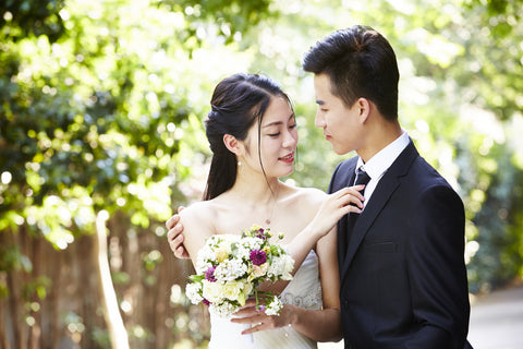 young asian groom kissing Japanese bride outdoors during wedding ceremony.