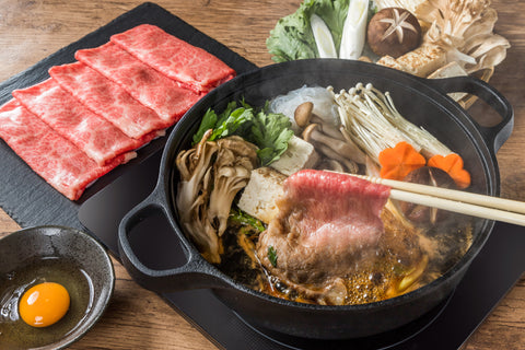 Sukiyaki plate with raw egg and vegetables as side dishes.