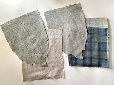 4 cut pattern pieces are shown - two leaf-shaped pieces from a light green fabric, and two rectangle pieces; one from a light tan fabric, the other with light green, and a pocket of blue plaid
