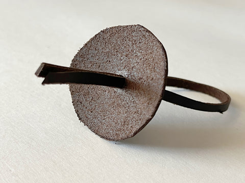 One leather circle is shown with both ends of a thin leather strip threaded through it.