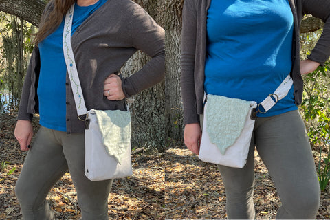 A finished beige Satchel with green Leaf flap is shown being worn two ways - long, across the body and as a hip pouch. The woman modelling it is wearing a blue tshirt, green pants, a brown sweater, and is surround by a backdrop of trees.