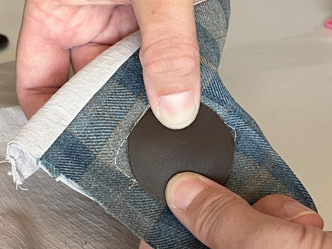 The nearly-finished leather hardware we are creating is shown, again, from the lining side of the Satchel Front. An unpunched leather circle is being glued to cover the pop tab and leather strip ends, creating a nice smooth back to the leather hardware.