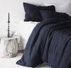 bedroom scene with 100% linen bed-in-a-bag matching bed set including duvet comforter cover two pillow shams smooth texture mid-weight St. Barts linen fabric twin queen king calking sizes ink navy dark blue color