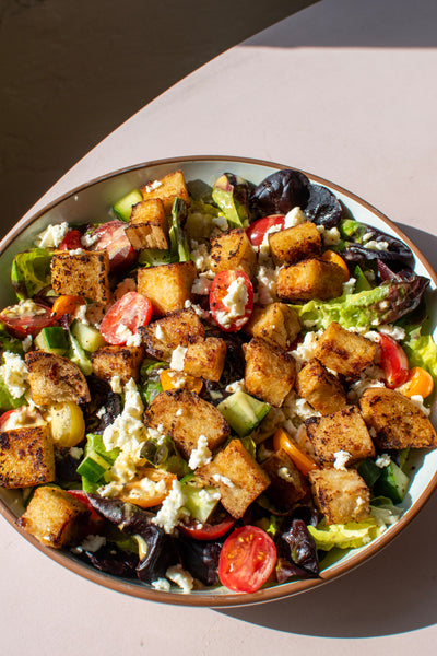 Bread SRSLY Miso Butter Croutons atop a fresh garden salad in a large bowl