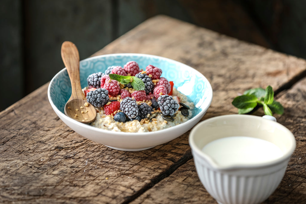 Porridge Schale Himbeeren Brombeeren Erdnüsse Kürbiskerne Milch Minze