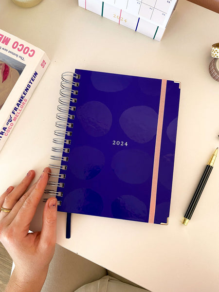 planner azul royal 2024 meg e meg sobre mesa de estudos