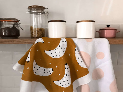 esta imagem tem potes de comida em cima de uma prateleira com panos de prato pendurados
