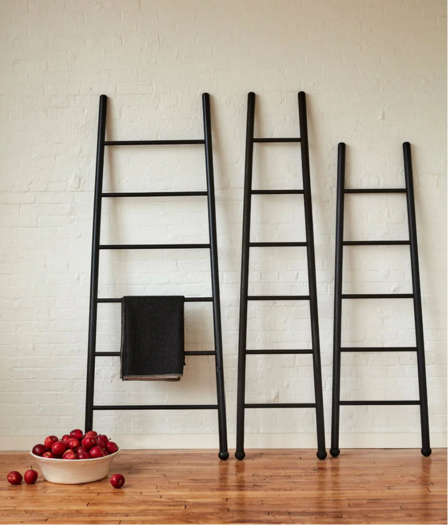 three bloak ladders against wall with apples