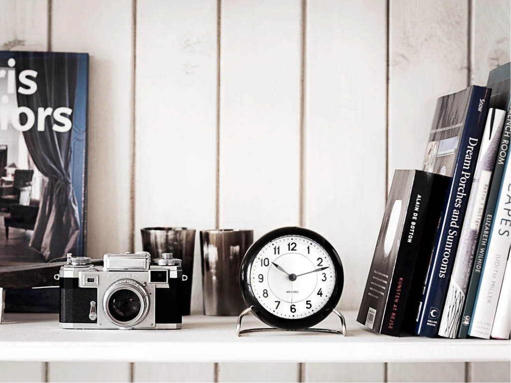 station clock on shelf with camera and books