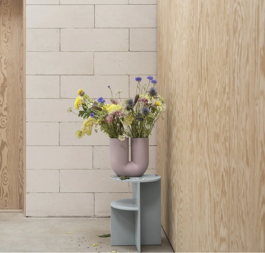 Pink kink vase on side table with flowers