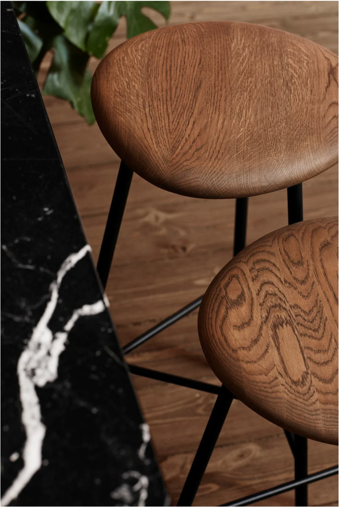 two wood pebble bar stools next to marble counter