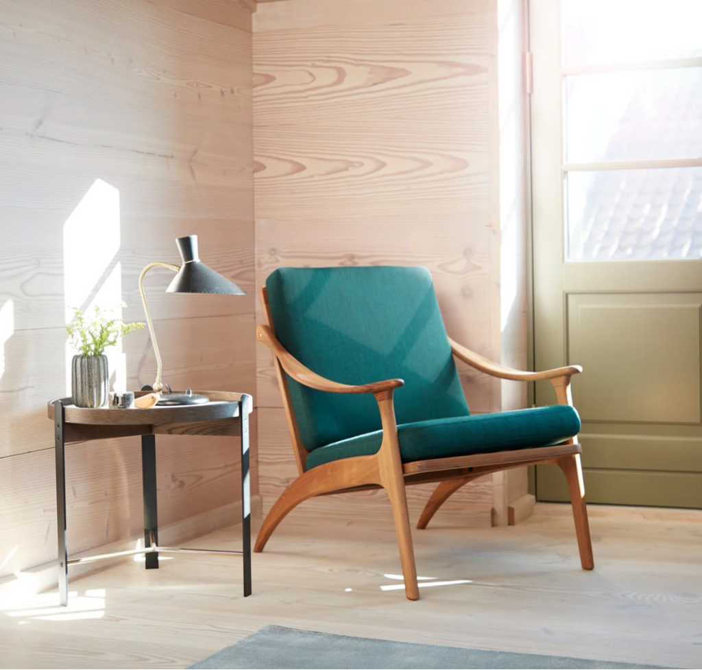 teal upholstered lean back lounge chair in corner with side table and lamp