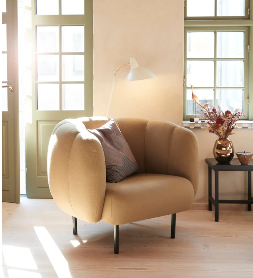 cape lounge chair in living room with natural sunlight, side table, and lamp