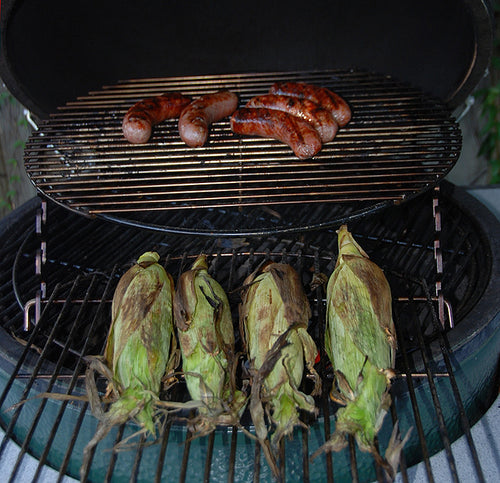 XL Big Green EGG Expander with XL Adjustable Rig on top grilling 4 ears of corn below 5 brats inside an XL Big Green EGG.