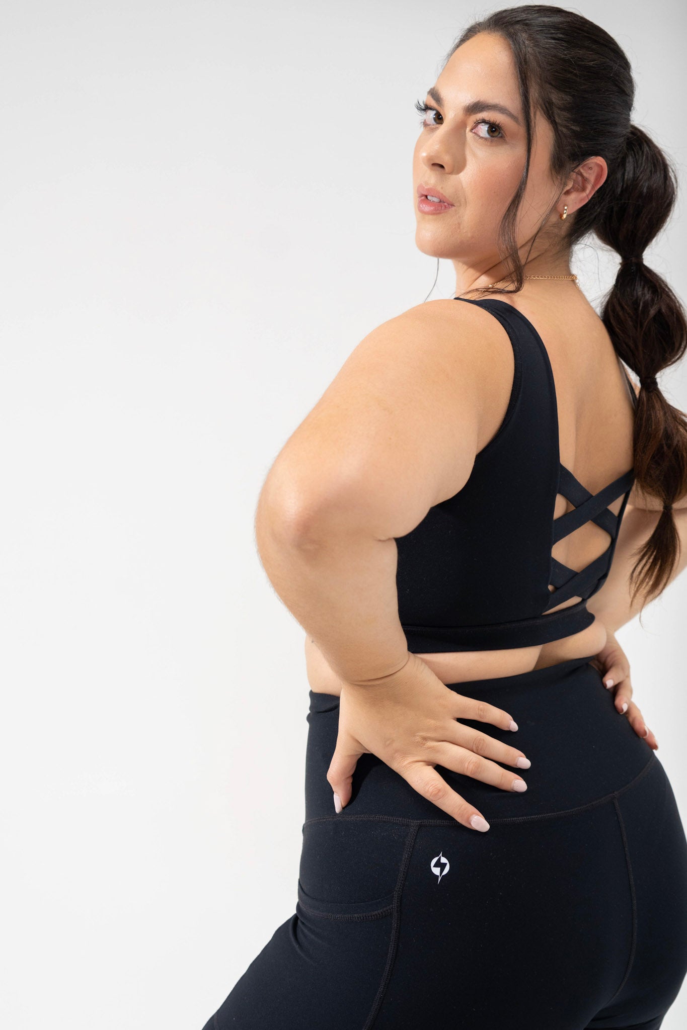 model wears the plus size corset bra in black, cute activewear criss cross sports bra from the POPFLEX basics collection