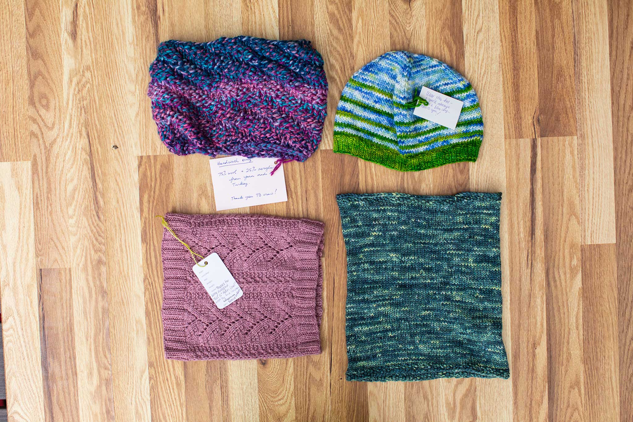 Clockwise: a blue and green hat, a green and blue cowl, a pink and red cowl, and a blue/purple/red cowl.