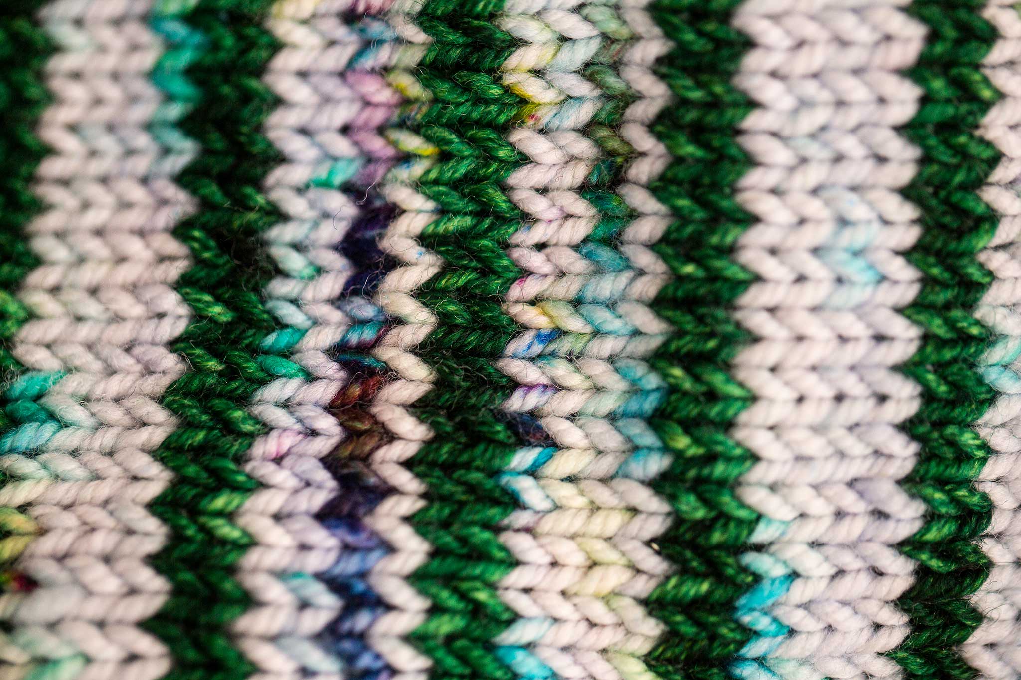 Close-up of a knitted work of art; white, blues, purples and greens are amongst the colors.