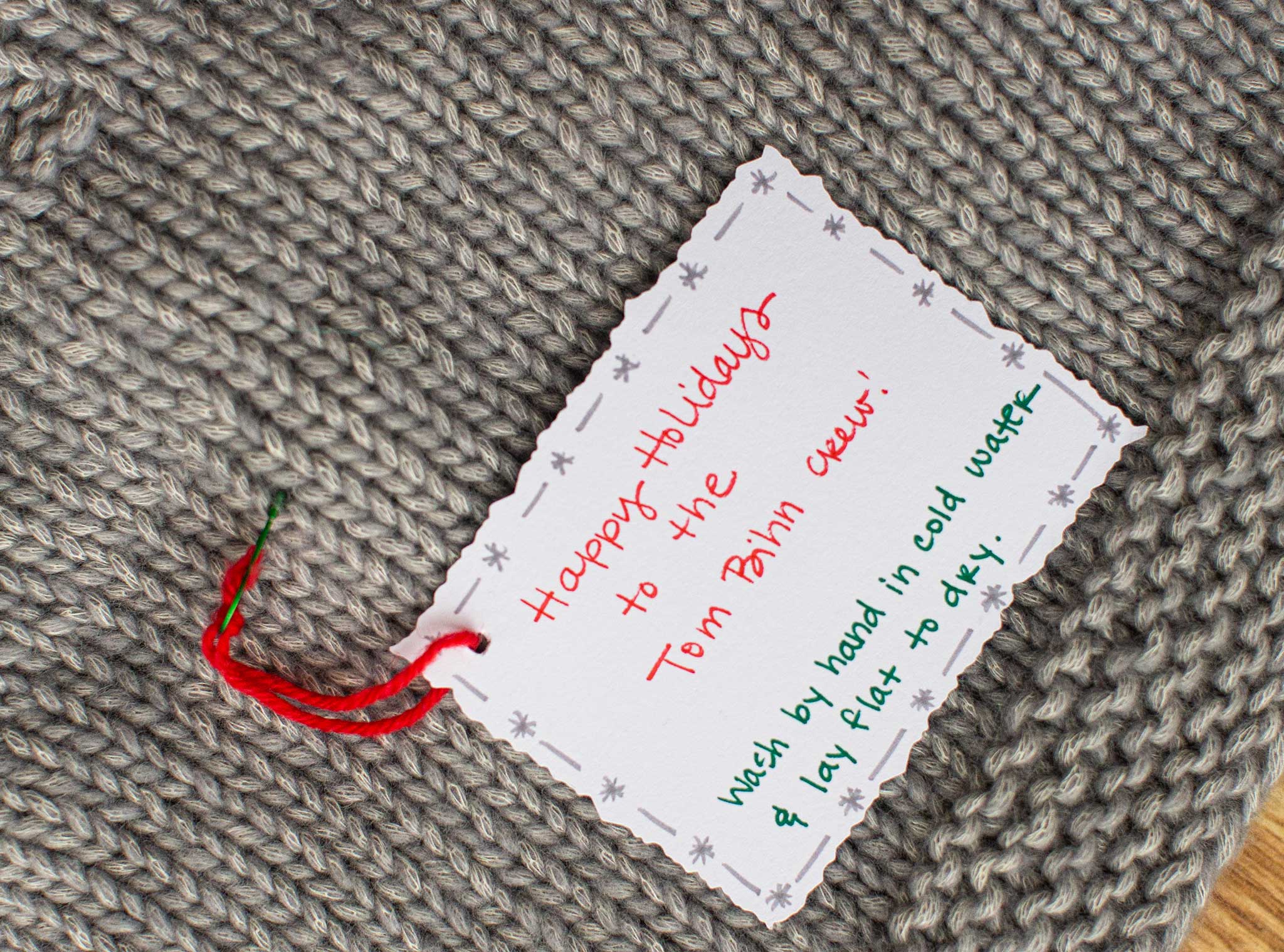 A card attached to one of the items. It says: "Happy Holidays to the TOM BIHN Crew! Wash by hand in cold water and lay flat to dry."