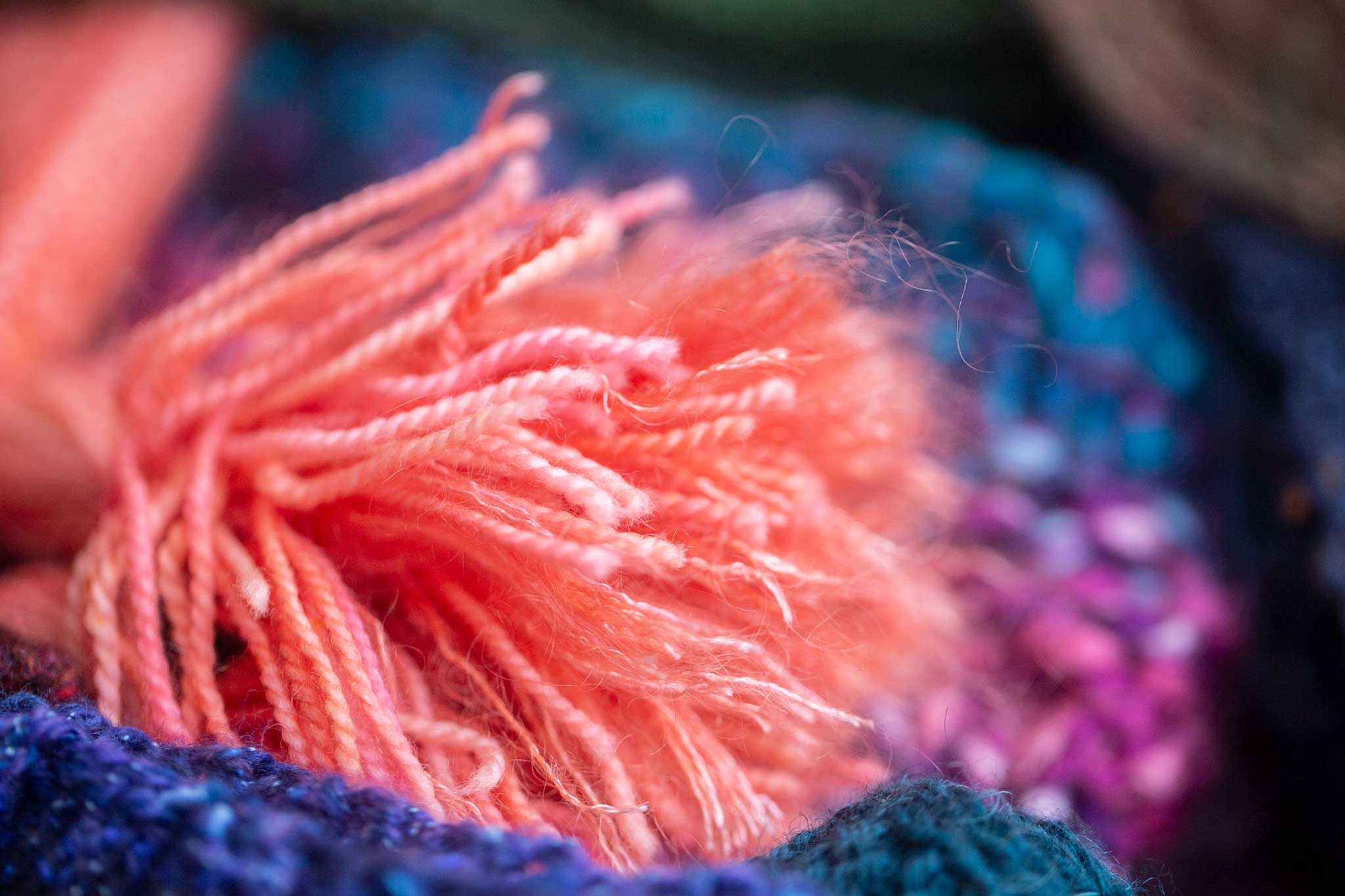 Close-up of a knitted pompom on a peach colored shawl.