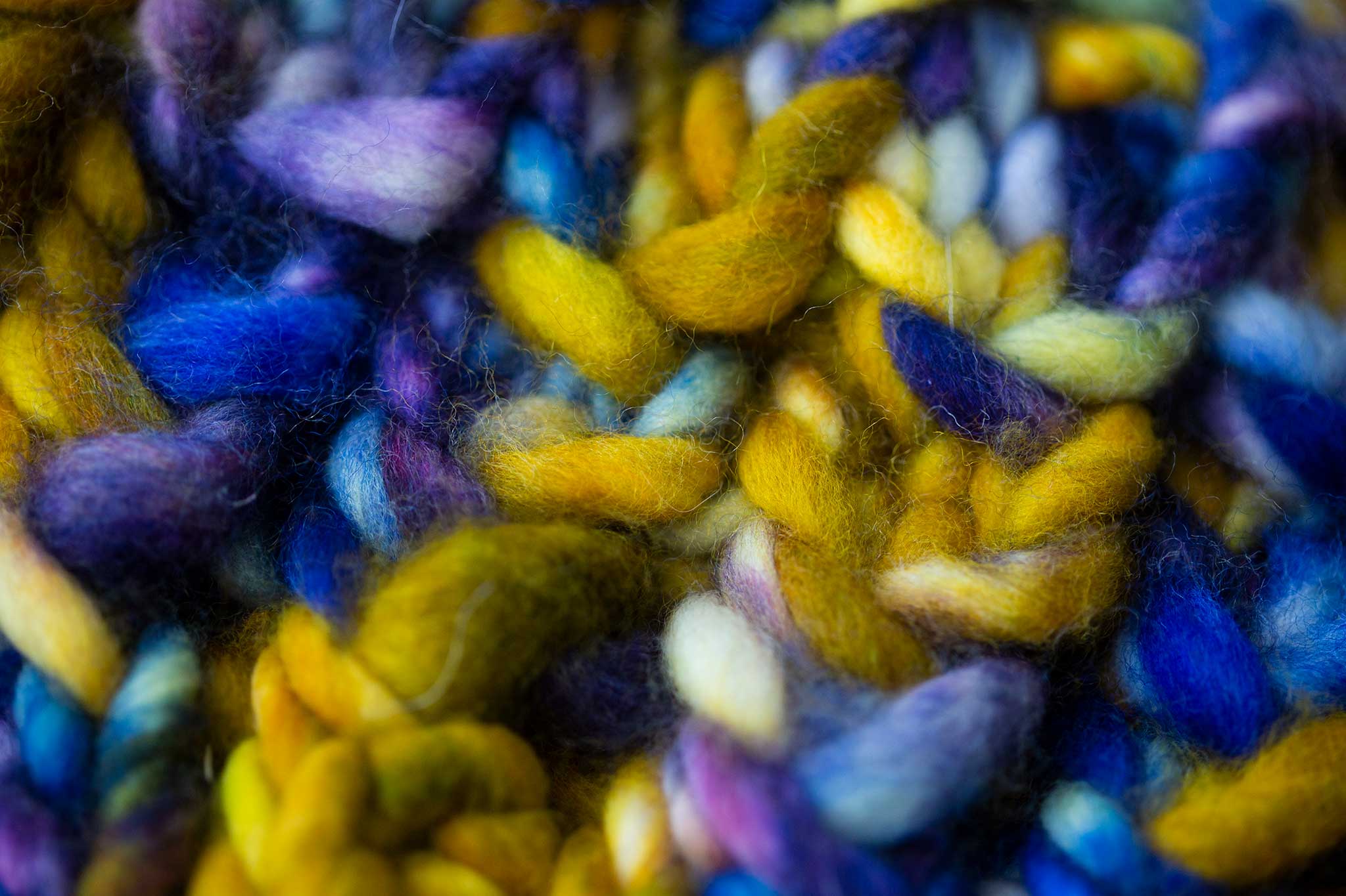 Close-up of a gorgeous thick knit in gold, pinks, purples, and blues.