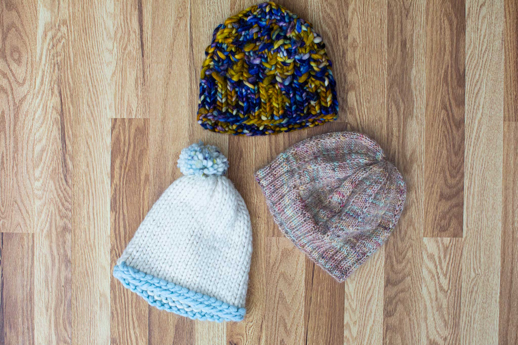 Three hats! Multi-color, grey, and white/light blue with a pompom on top.