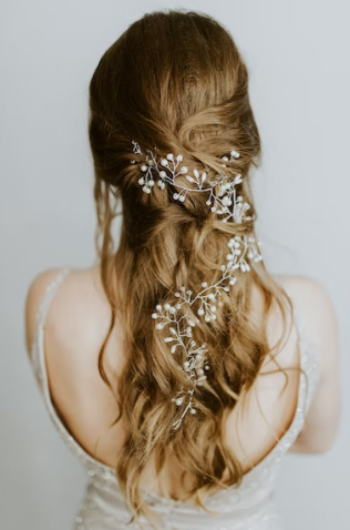  A woman with loose curls and flowers braided into her hair. 