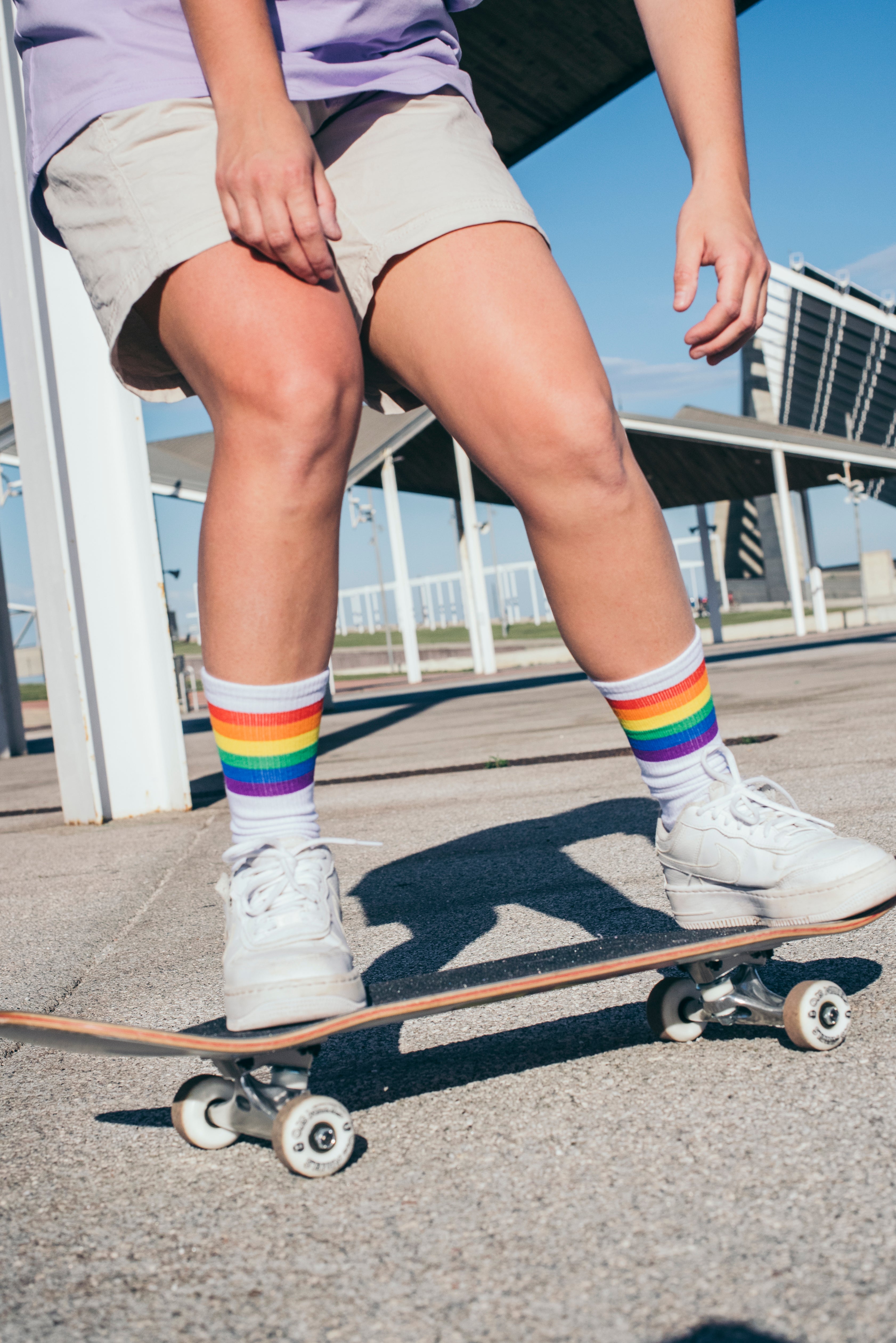 Person from the waist down wearing Rainbow Pride socks and skateboarding