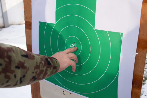 man pointing at hole on green paper target