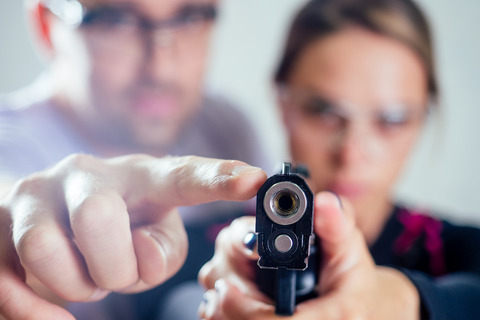 man helping woman aim gun