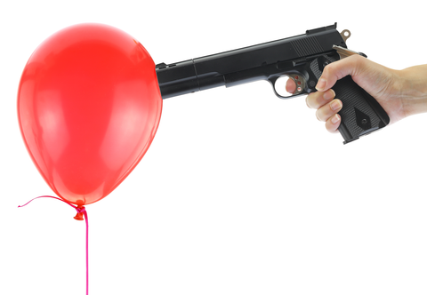 man pointing at red balloon with gun