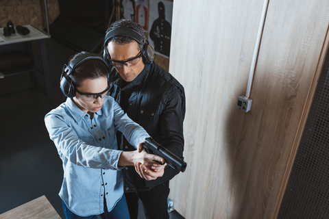 instructor helping woman aim gun at the range