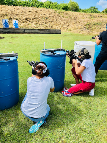 woman behind blue barrels aiming at shooting targets