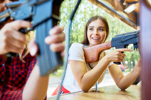 woman with rifle mounted on shoulder smiling at man