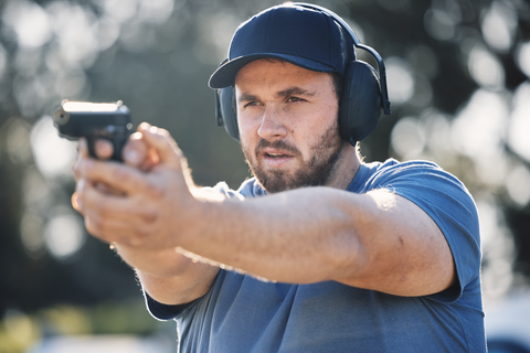 man with safety equipment aiming handgun