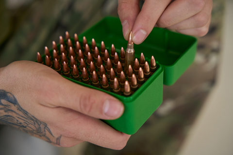 man placing bullets in green box