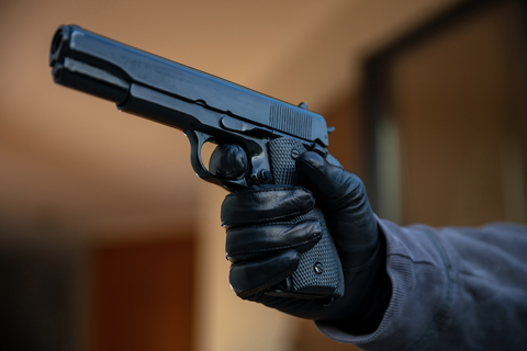 man aiming gun wearing glove