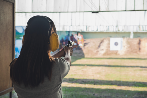 woman with hearing protection aiming gun at targets at an outdoor range