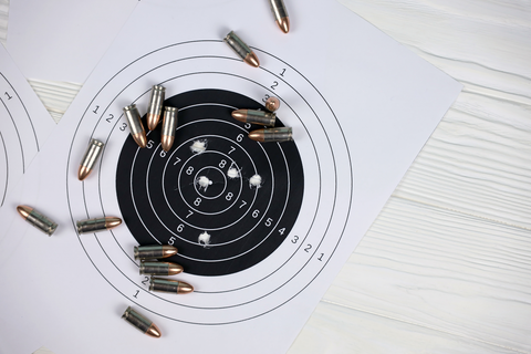 paper shooting target with bullet marks and bullet casings