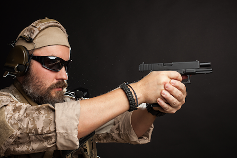 man with earmuffs holding a handgun