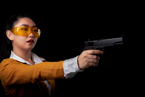woman with protective eyewear holding a handgun