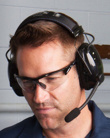 A man wearing an electronic earmuff providing adequate noise reduction to hear conversations and other safe noises.