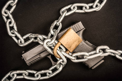 A handgun with a lock and chain tied around the trigger