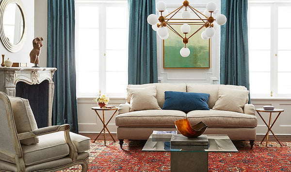 Living room with a fireplace, cream sofa, turqouise curtains and decorative chandelier.