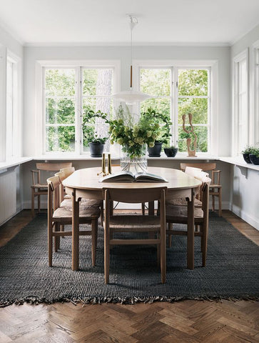 Dinning room with Dark brown rug under wooden dinning table and chairs